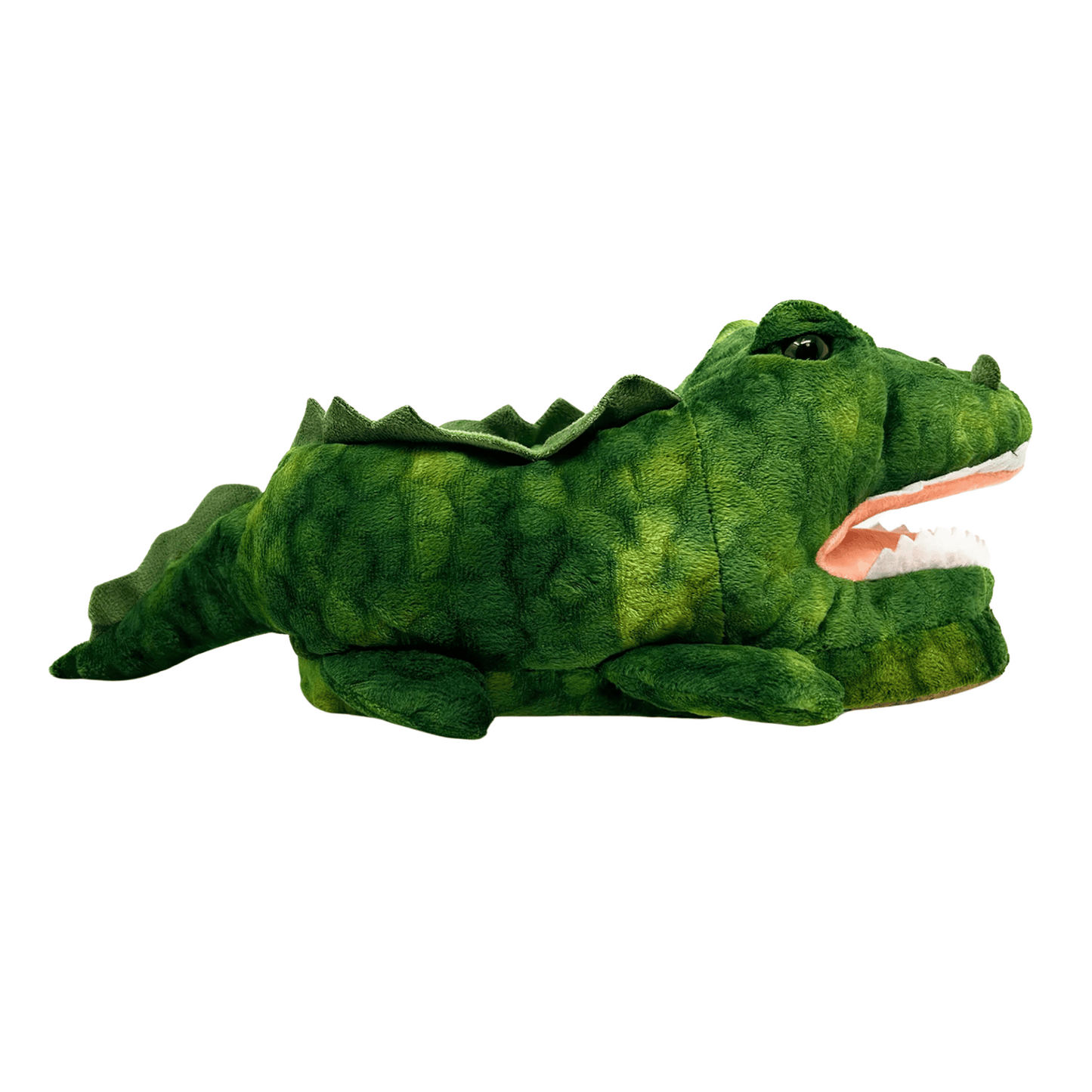 A side view of the green Kids Alligator Slippers designed with dark green lines to create a sense of scales. The alligator slippers are bearing a pink mouth, white full set of teeth, four little tiny legs, black and green eyes, nostrils, a tail including ex "scales", and "scales" around where the feet slip in.